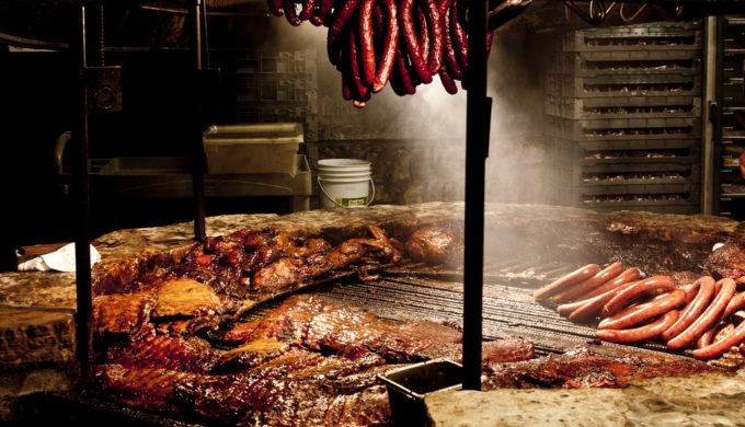 Different sausage types cooking on a pit at Salt Lick