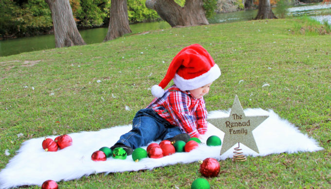 toddler boy playing with Christmas balls outside on a rug