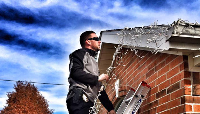 Centerton, AR officer on ladder hanging Christmas Lights