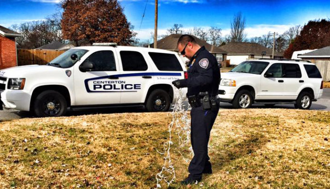 Centerton, AR Police Officer sorting out a cord of Christmas Lights